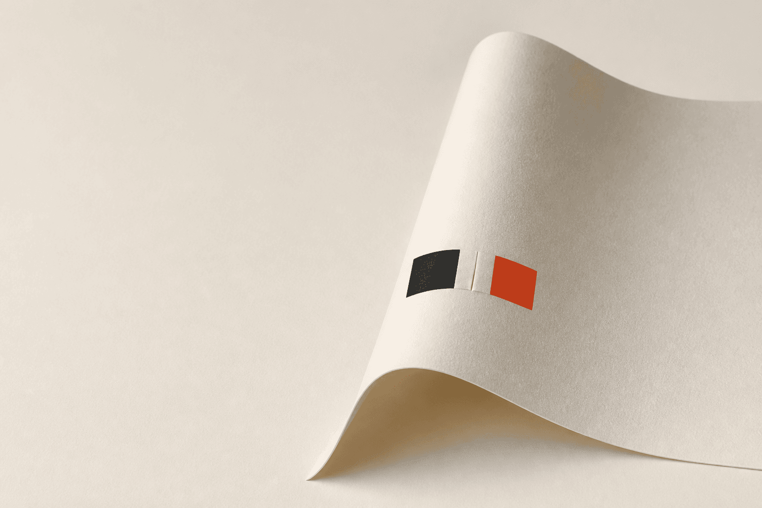 A warm cream paper sheet rises into a realistic fold beside one charcoal and one coral mark.